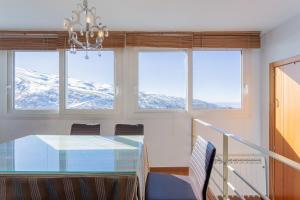 comedor con mesa de cristal y 3 ventanas en Apartamentos Sierra Nevada Prime Bluettravel, en Sierra Nevada