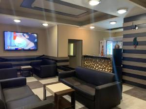 a waiting room with couches and a flat screen tv at Borovets Green Hotel in Borovets
