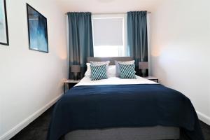 Schlafzimmer mit einem Bett mit blauen und weißen Kissen in der Unterkunft Macintosh Upper in Bellshill