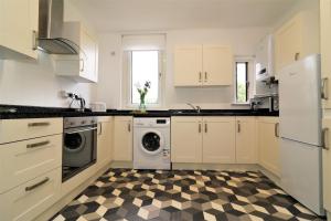 eine Küche mit weißen Schränken und einem karierten Boden in der Unterkunft Macintosh Upper in Bellshill