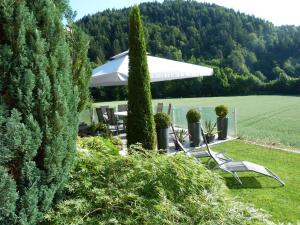 a group of chairs and an umbrella in a garden at Ferienhaus Blümel inkl. freier Strandbadeintritt in Velden am Wörthersee