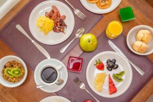 uma mesa com pratos de alimentos para o pequeno-almoço e uma chávena de café em Hotel Água de Coco em Maceió