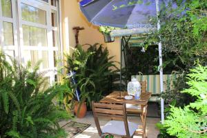 Il Giardino di Laura Private Rooms Mondello في مونديلّو: طاولة وكرسي مع مظلة ونباتات