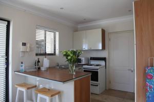 a kitchen with white cabinets and a counter with stools at Mossel is the Gem of Yzerfontein in Yzerfontein