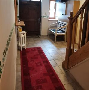 a hallway with a red rug on the floor and a staircase at Pension Nachtigall in Gottfrieding