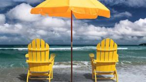 南帕诸岛Charming SPI family condo - walking distance to the beach, Sleeps 6, Third Floor, 2025 Traveler Award的海滩上的两张黄色椅子和一把遮阳伞