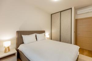 a bedroom with a large white bed and a closet at Athos Square Apartments in Podgorica