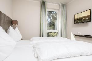 two white beds in a hotel room with a window at Strandhaus JUli in Baabe