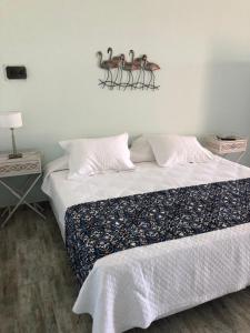 Un dormitorio con una cama con pájaros en la pared. en Las Piedritas Casa de Mar Loft, en Las Grutas