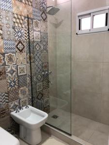 ein Bad mit einem WC und einer Glasdusche in der Unterkunft Las Piedritas Casa de Mar Loft in Las Grutas