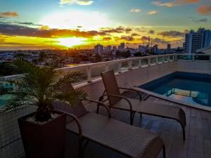 un balcón con sillas y una piscina con puesta de sol. en Atmosfera Hotel en Feira de Santana