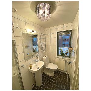 a bathroom with a sink and a toilet and a chandelier at Hotell Värend in Växjö