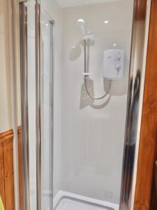 a shower stall with a white shower curtain at Windhaven Camping and B&B in Thurso