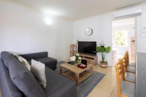 a living room with a gray couch and a tv at Lotus Stay Manly - Apartment 31G in Sydney