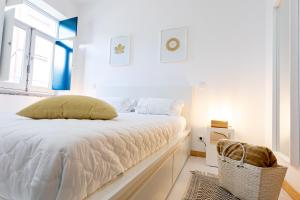 a white bedroom with a bed and a window at Casa da Porta Azul in Aveiro