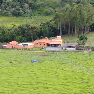 dom w środku zielonego pola w obiekcie Sítio Pé da Serra - Pousada Rural w mieście Capitólio