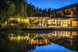 a building with lights next to a body of water at Session Hotel Ráckeve in Ráckeve