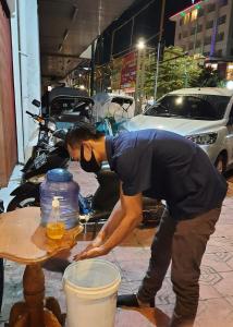 a man bending over a table in front of a jug at The Cabin Tugu Hostel in Yogyakarta