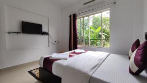 a white bedroom with a bed and a window at Green Tea View in Munnar