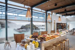 Silica Hotel at Blue Lagoon Iceland في غريندافيك: طاولة طويلة عليها طعام في غرفة بها نوافذ