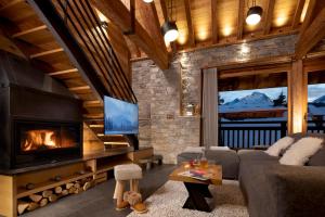 a living room with a fireplace and a couch at Chalet Prestige l'Atelier Lodge in Les Deux Alpes