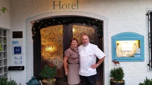 un hombre y una mujer parados frente a una puerta en Hotel Jägerhof garni en Bernau am Chiemsee