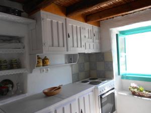 a kitchen with white cabinets and a stove and a window at Το σπίτι του Παππού. in Patmos