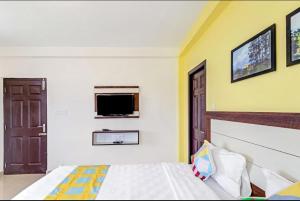 a bedroom with a bed and a tv on the wall at Brown Tree Resorts in Ooty