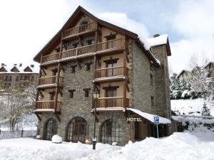 un bâtiment avec un balcon sur le côté de celui-ci dans la neige dans l'établissement Hotel Bocalé, à Sallent de Gállego