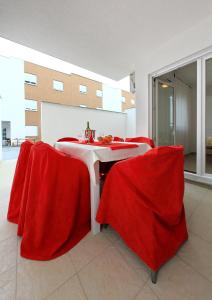 a dining room with red chairs and a table at Apartment Village Nin in Nin