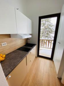 a kitchen with white cabinets and a large window at Apartman Maris in Šišava