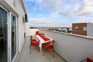 a balcony with a white table and red chairs at Apartment Village Nin in Nin