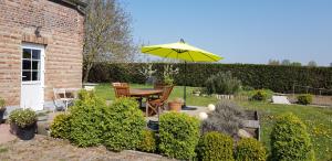 a patio with a table and a yellow umbrella at La Ceriseraie in La Gorgue