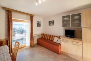 a living room with a couch and a tv and a window at Apartment Pustertal in Mühlbach