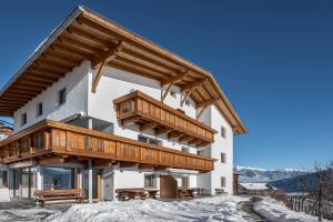 a building with wooden balconies on it in the snow at Apartment Pustertal in Mühlbach