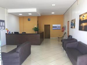 a lobby with a waiting room with couches and a counter at Hotel Novo Lar in Cuiabá