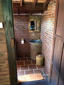 a small bathroom with a brick wall and a tub at Alas Arum Ecolodge in Tabanan