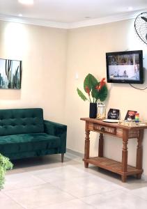 uma sala de estar com um sofá verde e uma mesa em Pousada Dubai em Itabuna