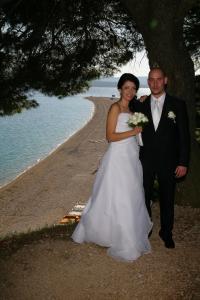 a bride and groom standing under a tree on the beach at Villa Jasmin in Bol