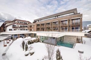 a building with a pool in the snow at Hotel Restaurant Langgenhof in Brunico