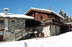 une cabane en rondins dans la neige avec un balcon dans l'établissement Aparthotel Foyer d'antan SUITE con caminetto hammam o vasca idromassaggio, à Brusson
