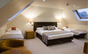 Schlafzimmer im Dachgeschoss mit 2 Betten und einem Stuhl in der Unterkunft Stirrups Hotel in Bracknell