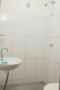 a white bathroom with a sink and a toilet at Hotel Novo Lar in Cuiabá
