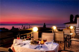a table with wine glasses on a balcony at night at CORFU PELAGOS HOTEL in Moraitika