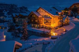 a house in the snow at night at Dolomites Apartments Ciasa Vally in San Cassiano