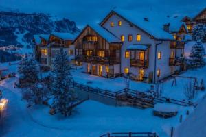 
a house with a snow covered cabin and trees at Dolomites Apartments Ciasa Vally in San Cassiano
