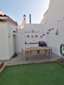 een patio met een houten tafel en stoelen aan een witte muur bij Lala´s house in Ingenio