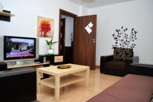 - un salon avec une télévision, un canapé et une table dans l'établissement Gamma Group Accommodation, à Bucarest