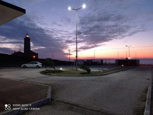 a car parked in a parking lot with a lighthouse at São Pedro de Moel by Campigir in São Pedro de Moel