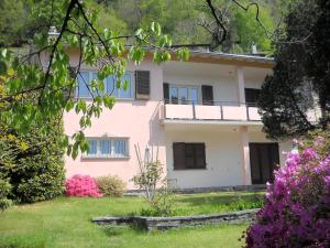 a pink house with blue windows and flowers at Casa Alice in Locarno